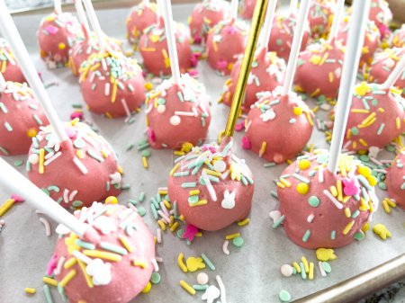 Foto de Arreglados cuidadosamente en pergamino, estos pasteles rosados sumergidos a mano son un regalo juguetón, adornados con un arco iris de aspersiones que agregan un toque festivo a las delicias dulces. - Imagen libre de derechos