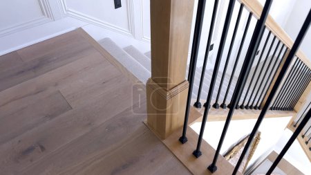 La imagen captura el detalle de una escalera moderna bien diseñada, forrada con una lujosa alfombra beige, complementada con paredes blancas y balaustres de madera..