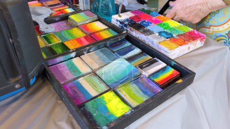 The photo displays two open palettes of colorful face paint, each square brimming with bright, shimmering hues, ready to transform faces into works of art.