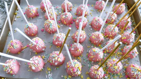 Arreglados cuidadosamente en pergamino, estos pasteles rosados sumergidos a mano son un regalo juguetón, adornados con un arco iris de aspersiones que agregan un toque festivo a las delicias dulces.