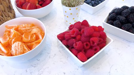 Eine Auswahl lebhafter, frisch geschnittener Erdbeeren, Orangen, Himbeeren und Brombeeren in verschiedenen Schalen, bereit für einen gesunden Genuss.