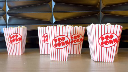 Reihen frisch gefüllter gestreifter Popcornboxen warten auf eifrige Kinobesucher, deren nostalgisches Design die Vorfreude auf Unterhaltung noch steigert..