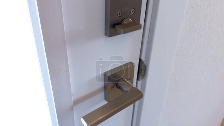 Foto de Un primer plano de una manija elegante de la puerta negra montada en una puerta blanca nítida, destacando un diseño casero minimalista y contemporáneo. - Imagen libre de derechos