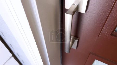 Photo for A person hand is captured in the process of opening a door using a brushed metal handle, portraying the action of entering or leaving a room. - Royalty Free Image