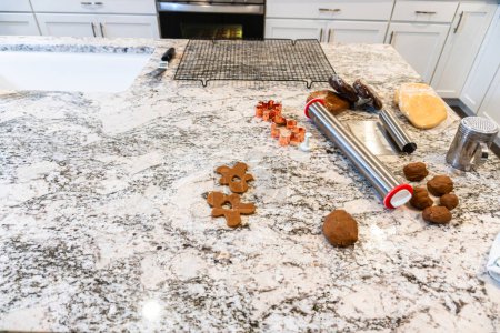 Téléchargez les photos : Dans une cuisine blanche contemporaine, la pâte à biscuits au pain d'épice est habilement déroulée, préparant le terrain pour une délicieuse gâterie de vacances. - en image libre de droit