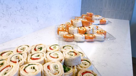 Téléchargez les photos : Un étalage alléchant de sandwichs aux pinwheel remplis de légumes frais et de charcuteries, parfait pour tout rassemblement ou déjeuner rapide. - en image libre de droit