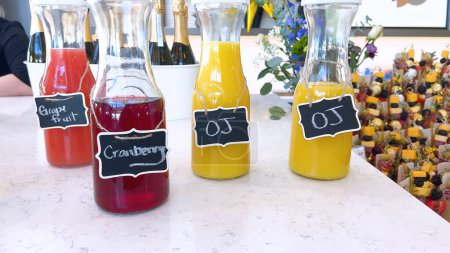 Photo for A catering event setup featuring glass carafes filled with grapefruit, cranberry, and orange juice. Each bottle is clearly labeled, providing refreshing beverage options for guests. - Royalty Free Image