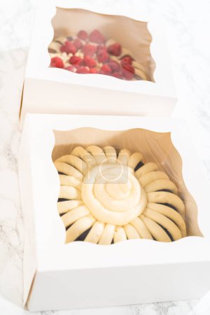 Photo for Two delightful homemade bundt cakes, each adorned with creamy cream cheese frosting, elegantly packaged in white paper boxes with a clear window to showcase their scrumptious appeal. - Royalty Free Image