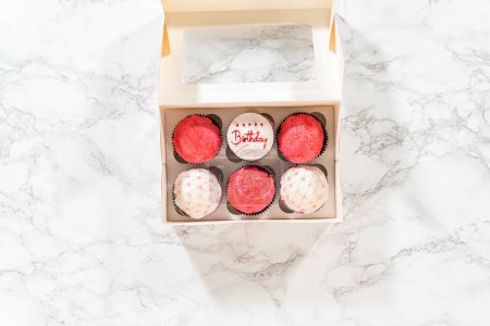 Photo for Flat lay. The birthday cupcakes, beautifully embellished with fondant decorations, are being carefully placed into white paper boxes, ready for their grand presentation. - Royalty Free Image
