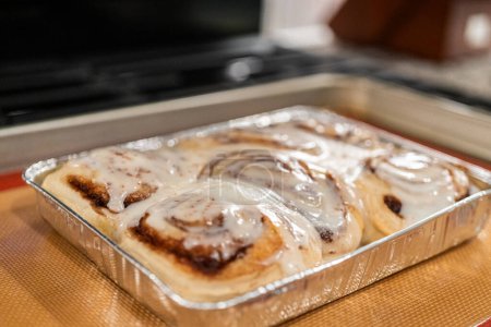 Just out of the oven, cinnamon rolls cool on a silicone baking mat, their icing glistening under the kitchen lights.