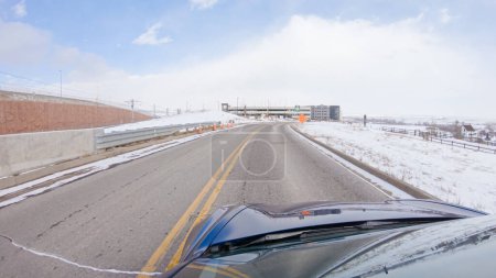 Navigating a frontage road post-winter storm offers a serene drive. The surrounding landscape, blanketed in snow, contributes to the peaceful and picturesque environment, enhancing the driving