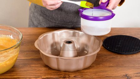 Carefully greasing a bundt cake pan in preparation for baking a delicious gingerbread bundt cake with caramel frosting.