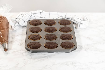 Foto de Justo fuera del horno, estos deliciosos cupcakes de chocolate ahora descansan y se enfrían en el mostrador de la cocina, llenando el aire con su aroma tentador. - Imagen libre de derechos