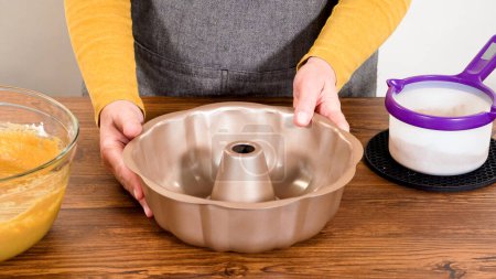 Carefully greasing a bundt cake pan in preparation for baking a delicious gingerbread bundt cake with caramel frosting.