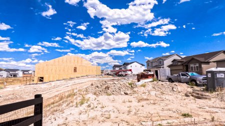 Foto de Denver, Colorado, Estados Unidos-30 de agosto de 2023-El nuevo vecindario residencial revela el marcado contraste entre el marco de madera en bruto de un edificio en construcción y las casas terminadas en el fondo - Imagen libre de derechos