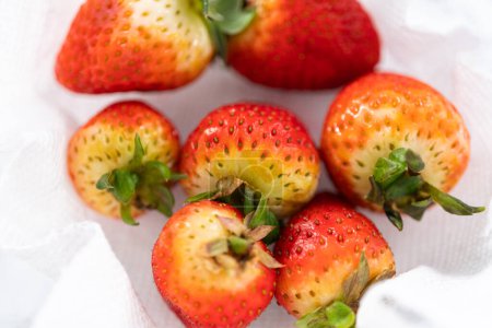 Téléchargez les photos : Les fraises fraîchement lavées et séchées sont soigneusement disposées dans un bol en verre doublé d'une serviette en papier, prêtes à être grignotées ou utilisées ultérieurement.. - en image libre de droit