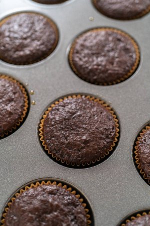Just out of the oven, these delectable chocolate cupcakes are now resting and cooling on the kitchen counter, filling the air with their tempting aroma.