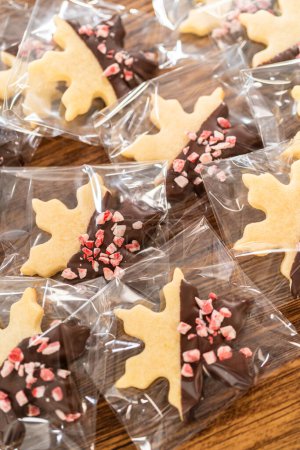 Photo for Carefully packaging Christmas cutout cookies, half-dipped in chocolate and presented in clear cellophane wrapping, perfect for festive gifting. - Royalty Free Image