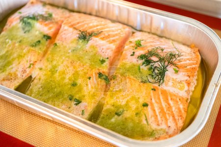 Discover the mouthwatering journey of salmon as its cooked to perfection in an oven, nestled in a foil tray, adorned with rich butter and tantalizing spices.
