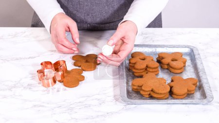 Photo for Gingerbread cookies, including a gingerbread man with a heart-shaped cutout, rest on a rustic metal tray against a marble countertop. - Royalty Free Image