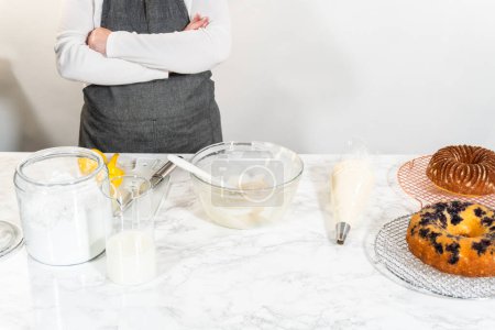 Téléchargez les photos : La dernière étape de ce délicieux voyage de cuisson consiste à piquer artistiquement le fromage à la crème soyeuse beurre glaçage au sommet des gâteaux bundt refroidis, créant un régal irrésistible. - en image libre de droit