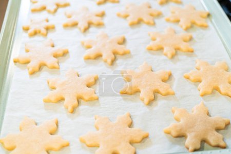 Foto de Dejar enfriar las deliciosas galletas de azúcar en forma de copo de nieve después de hornear, preparándolas para los regalos navideños festivos.. - Imagen libre de derechos