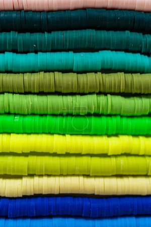 Téléchargez les photos : Une collection vibrante de perles d'argile, soigneusement disposées par couleur sur une table blanche, prête à inspirer les jeunes artisans à créer leurs propres bracelets uniques. - en image libre de droit