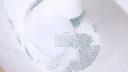 Foto de Elegante bañera blanca llena de agua, con un elegante grifo de níquel cepillado con agua que fluye suavemente en la bañera. Las bañeras de diseño moderno y el agua clara y tranquila sugieren una paz - Imagen libre de derechos