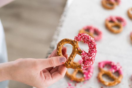 Foto de Recién sumergidos y todavía brillantes, estos pretzels crujientes están adornados con amor con chocolate rosa y una dispersión de chispas de colores, prometiendo una fiesta para los sentidos. - Imagen libre de derechos