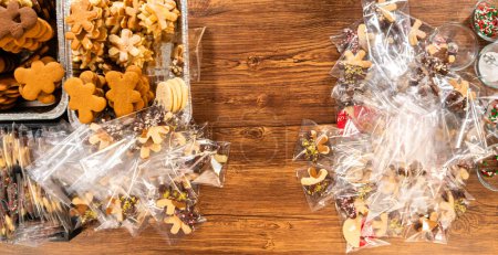 Téléchargez les photos : Emballage soigneux des biscuits découpés de Noël, à moitié trempés dans du chocolat, saupoudrés de noix concassées et présentés dans un emballage en cellophane transparent. - en image libre de droit