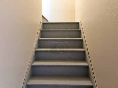 Entdecken Sie die typische Konstruktion einer unfertigen Treppe, die in den Keller eines Vorstadthauses führt und den Rohstoff- und Bauprozess zeigt.