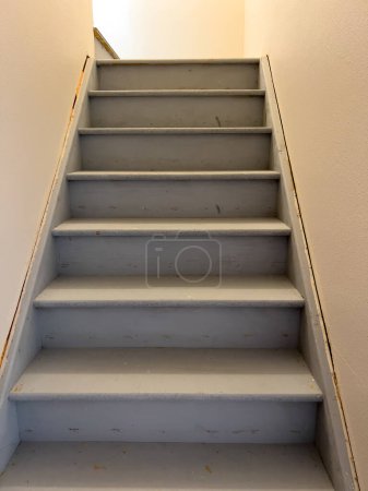 Entdecken Sie die typische Konstruktion einer unfertigen Treppe, die in den Keller eines Vorstadthauses führt und den Rohstoff- und Bauprozess zeigt.