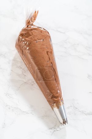 Photo for The chocolate icing is carefully transferred into a piping bag, ready to adorn the scrumptious cupcakes. - Royalty Free Image