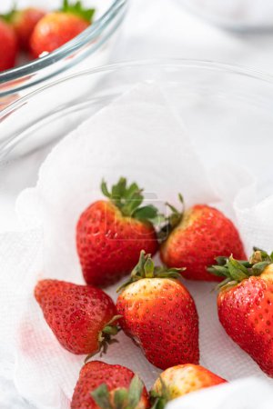 Photo for Bright red strawberries, interspersed with signs of mold, rest in a glass bowl lined with a paper towel on a white napkin, indicating improper storage techniques. - Royalty Free Image