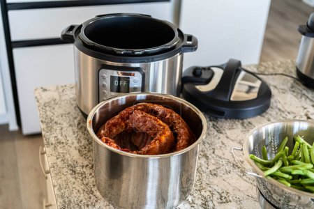 In a sleek modern kitchen, we are adding an extra layer of flavor to succulent baby back ribs by infusing them with a medley of spices in a multicooker-a mouthwatering feast in the making.