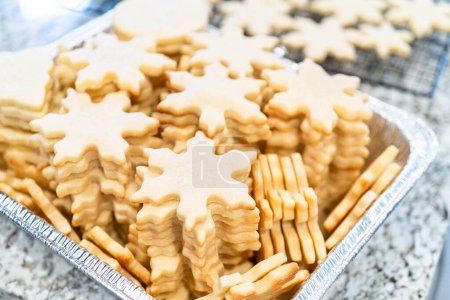 Photo for Carefully stacking the beautifully crafted snowflake-shaped sugar cookies into a foil pan, ready for freezing as delightful Christmas treats. - Royalty Free Image