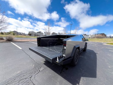 Téléchargez les photos : Denver, Colorado, USA-28 mars 2024-L'arrière distinctif d'un Cybertruck Tesla, capturé dans un parking vide, se distingue sur fond de maisons de banlieue sous un ciel bleu avec peluche - en image libre de droit