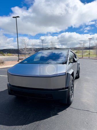 Téléchargez les photos : Denver, Colorado, USA-28 mars 2024-Le profil avant d'un Cybertruck Tesla est affiché, mettant en valeur ses lignes futuristes et son design robuste, garé dans un parking en plein air avec un ciel dynamique - en image libre de droit