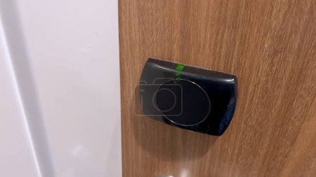 Foto de Vista de cerca de una mano de huésped usando una tarjeta de llave negra para abrir la puerta de una habitación de hotel, lo que demuestra la seguridad y conveniencia de los modernos sistemas de acceso al hotel. - Imagen libre de derechos