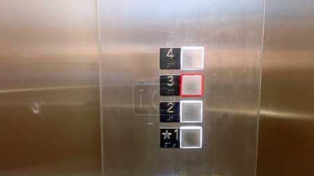 Ein Bedienfeld für den Aufzug, das eine Reihe von Fußbodenknöpfen zeigt, wobei die zweite und dritte Etage hervorgehoben sind, was die aktuelle Auswahl der Benutzer anzeigt.
