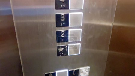 Ein Bedienfeld für den Aufzug, das eine Reihe von Fußbodenknöpfen zeigt, wobei die zweite und dritte Etage hervorgehoben sind, was die aktuelle Auswahl der Benutzer anzeigt.