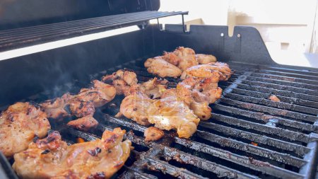 Photo for A close-up image capturing the process of grilling marinated chicken pieces, with a person expertly flipping them to ensure even cooking on a classic outdoor barbecue grill. - Royalty Free Image