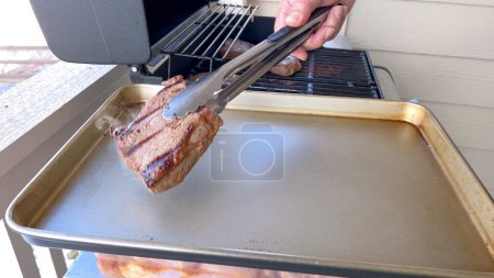 Téléchargez les photos : Plusieurs steaks épais avec des marques de grill cuisiner à la perfection sur un gril extérieur, capturant l'essence d'une journée de barbecue ensoleillée. - en image libre de droit