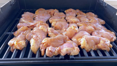 Photo for A close-up image capturing the process of grilling marinated chicken pieces, with a person expertly flipping them to ensure even cooking on a classic outdoor barbecue grill. - Royalty Free Image