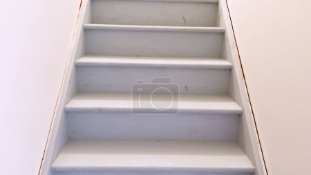 Foto de Vista de una escalera lisa pintada de blanco que desciende al sótano de una casa, caracterizada por sus líneas limpias y diseño minimalista. - Imagen libre de derechos