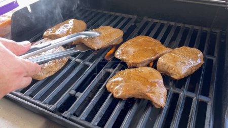 Mehrere dicke Steaks mit Grill markieren das Kochen in Perfektion auf einem Outdoor-Grill und fangen die Essenz eines sonnigen Grilltages ein.