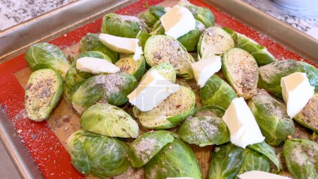 Photo for Fresh Brussels sprouts seasoned with spices and topped with slices of butter, arranged on a baking sheet, ready to be roasted to perfection. - Royalty Free Image