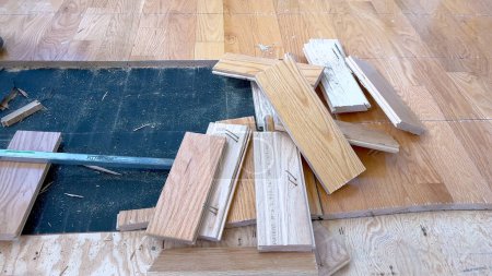 Photo for A scattered array of hardwood planks lies on a partially completed floor, highlighting the ongoing work of a home renovation project focused on installing new wood flooring. - Royalty Free Image