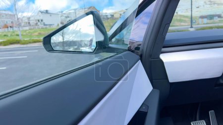 Téléchargez les photos : Une perspective de conducteur à l'intérieur du Cybertruck Tesla, mettant en valeur son intérieur spacieux et minimaliste avec un grand écran tactile et un volant futuriste, sur fond de paysage - en image libre de droit
