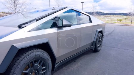 Photo for A Tesla Cybertruck stands out with its distinctive, futuristic design and metallic body parked on a suburban street, illustrating the blend of advanced automotive technology with everyday life. - Royalty Free Image